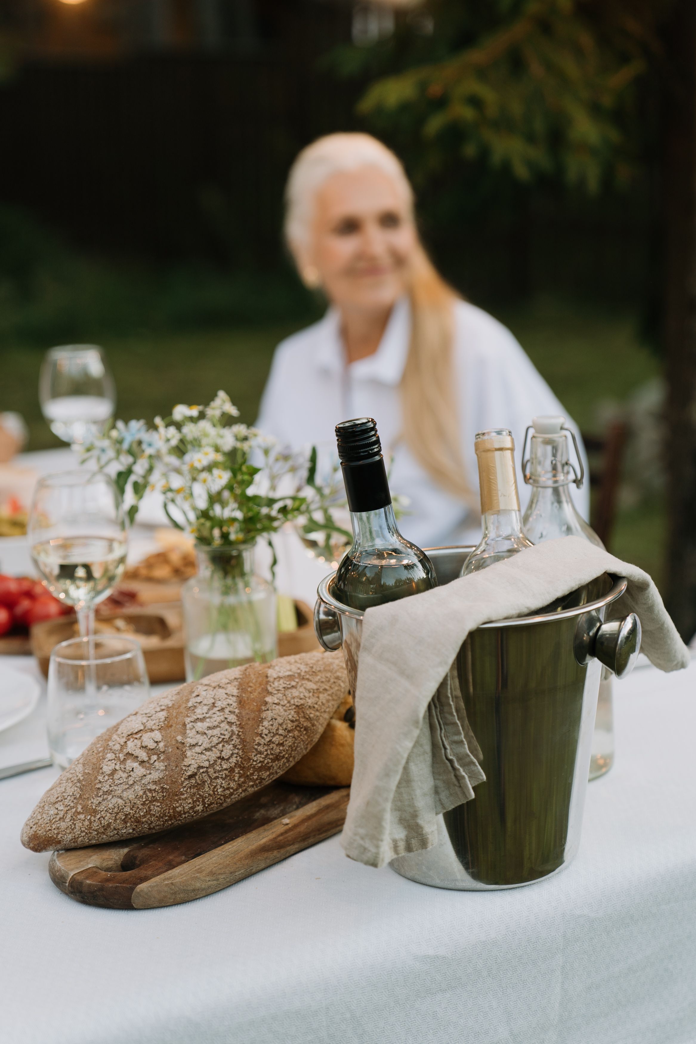 An outdoor dining table with bottles of wine and seasonal food at dusk
